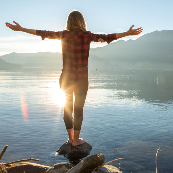 woman standing on a rock in lake
