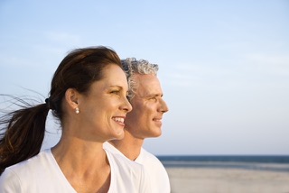 Side view of smiling middle aged couple on beach looking